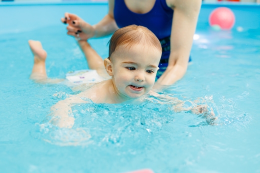 little cute baby boy swimming with instructor